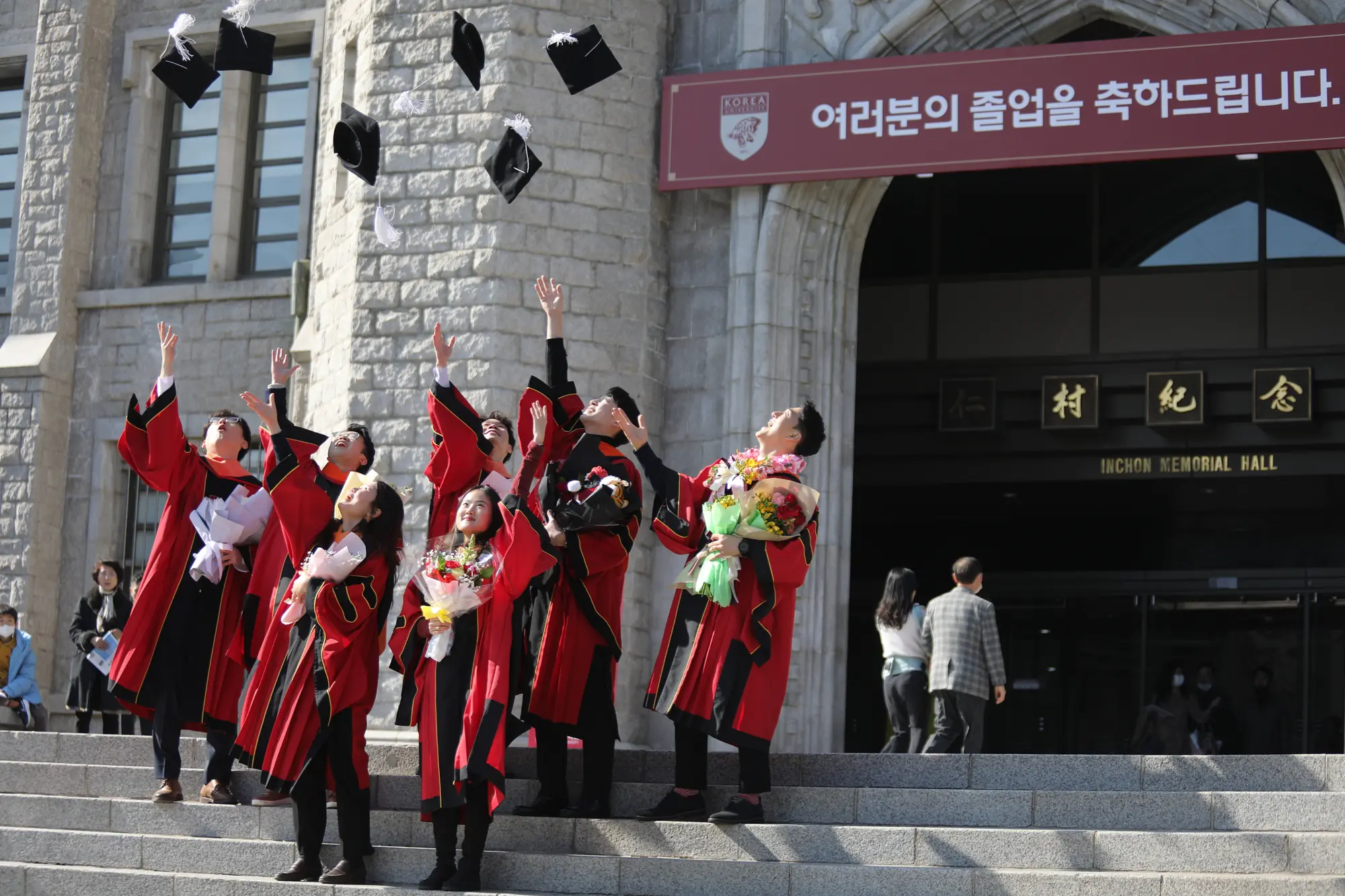 Graduates in gowns throwing their caps in the air on the steps of a university hall